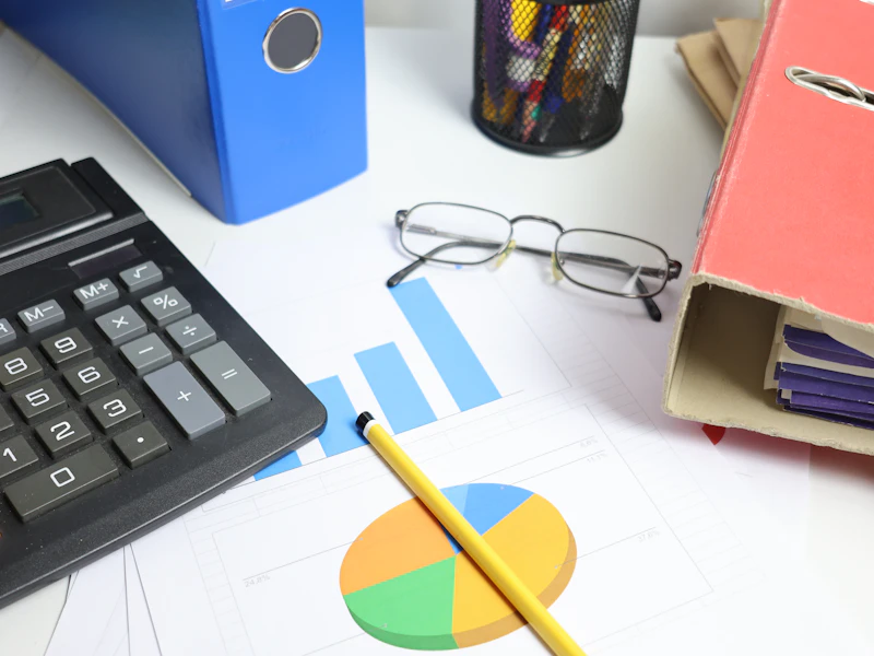 A desk with a calculator, printed charts and binders